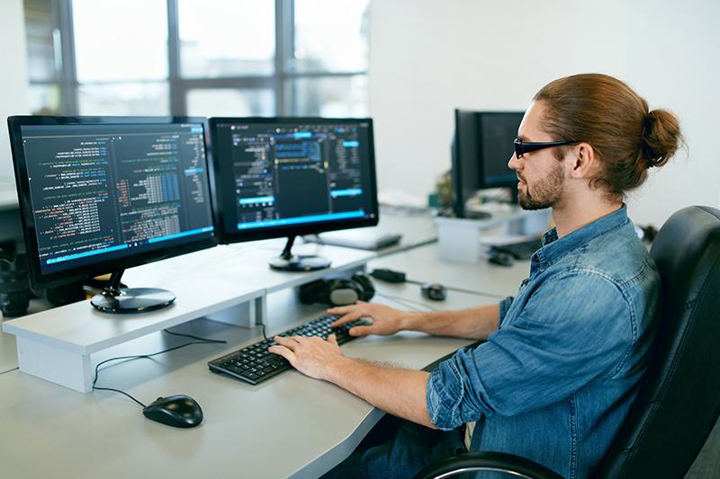 编程. 在电脑办公室用电脑工作的人, 坐在办公室里, 编写代码. 程序员输入数据代码, 在软件开发公司从事一个项目. 高品质图片.